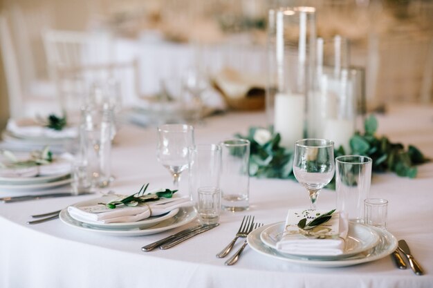 Set da tavola per la cena di nozze. Elegante arredamento bianco con vegetazione