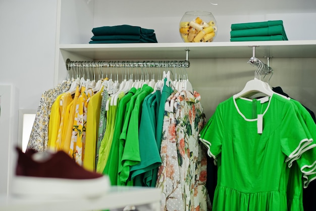 Set di abbigliamento femminile verde colorato su scaffali e scaffali nel negozio di abbigliamento nuovissimo boutique moderno Collezioni di abiti estivi primaverili