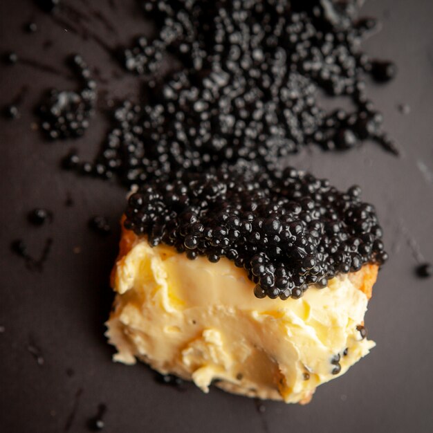 Set di burro e caviale nero su un pane su sfondo scuro. Veduta dall'alto.