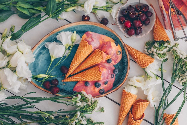 Set di fiori, frutta e gelato nel piatto blu su legno bianco. vista dall'alto.