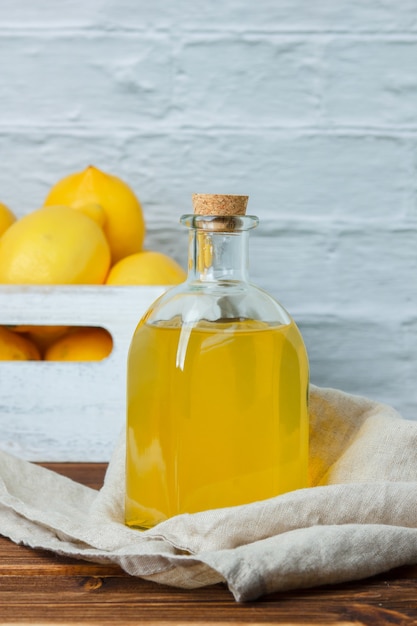 Set di limoni su cassa di legno e succo di limone su una superficie di legno. vista laterale. spazio per il testo