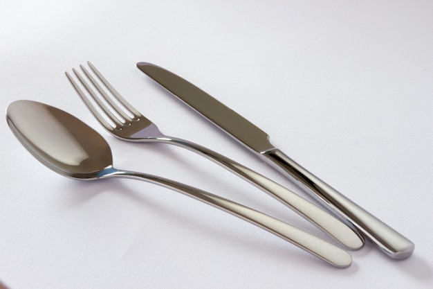 Set di posate con forchetta, coltello e cucchiaio isolato su sfondo bianco.