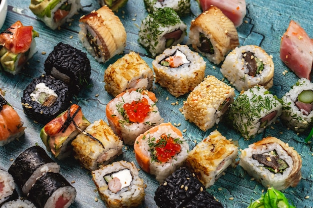 Set di sushi vista laterale rotoli di philadelphia con salmone e anguilla rotolo di sushi di riso selvatico aneto rotolo di calofornia e rotolo di alaska sul tavolo