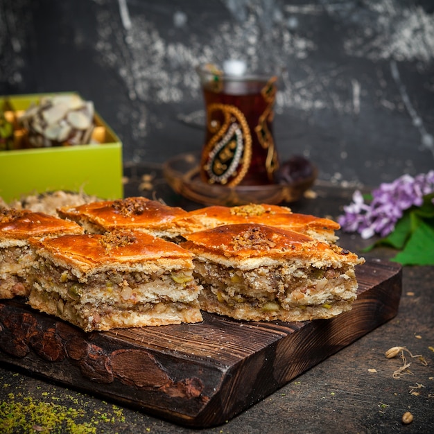 Set di tè, biscotti e baklava su uno sfondo di legno e nero. vista laterale.