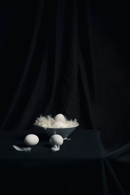Set di uova di gallina tra le piume in una ciotola sul tavolo