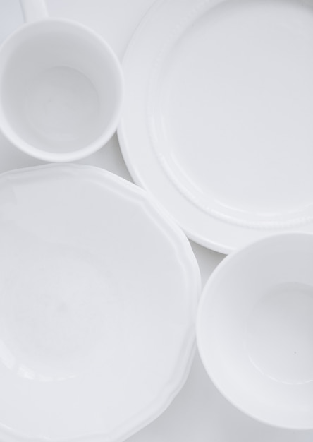 set di utensili bianchi da tre diversi piatti e una tazza su uno sfondo bianco