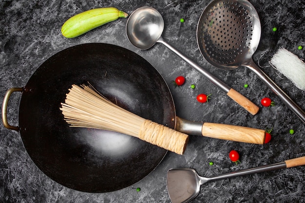 Set di utensili da cucina e padella su uno sfondo nero con texture. vista dall'alto.