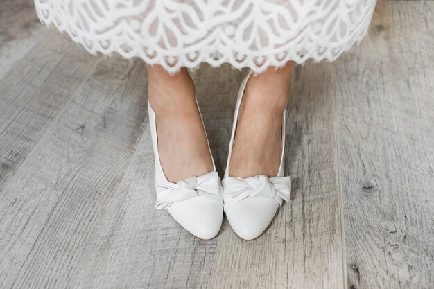 Sezione bassa della gamba della sposa che indossa scarpe eleganti bianche