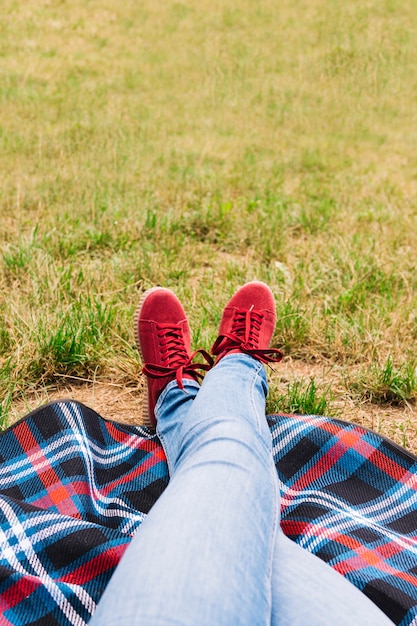 Sezione bassa della gamba incrociata della donna che indossa scarpe rosse sulla coperta