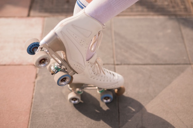 Sezione bassa della pattinatrice femminile con pattino a rotelle vintage bianco
