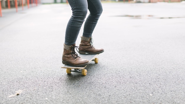 Sezione bassa dello skateboarder che guida lo skateboard