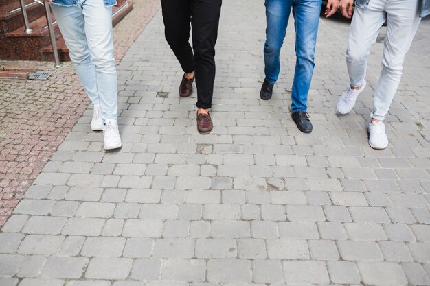 Sezione bassa di amici maschi camminando insieme sul marciapiede