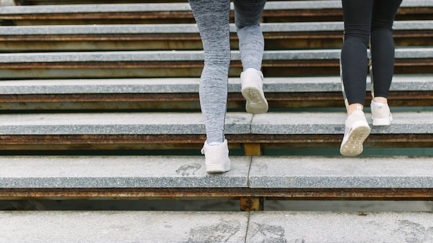 Sezione bassa di due corridori femminili che fanno jogging sulle scale