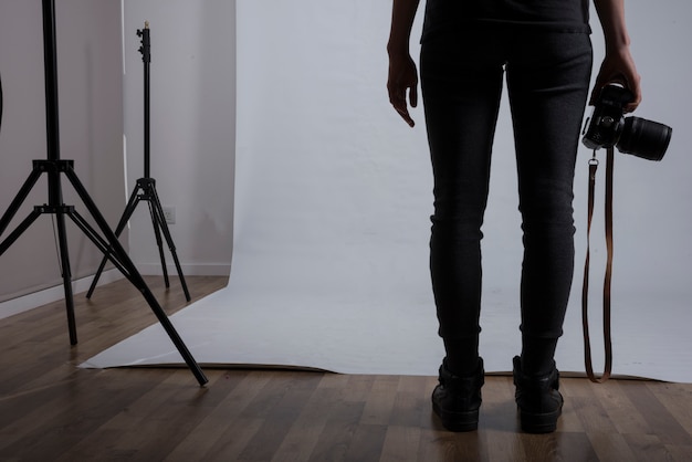 Sezione bassa di una macchina fotografica femminile della tenuta del fotografo nello studio della foto