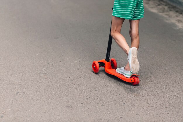 Sezione bassa di una ragazza in sella a scooter su strada