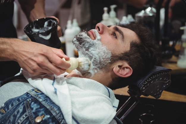 Sezione centrale del barbiere che applica la crema sulla barba dei clienti