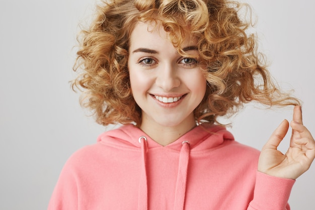 Sfacciata ragazza dai capelli ricci che sembra soddisfatta, sorridente