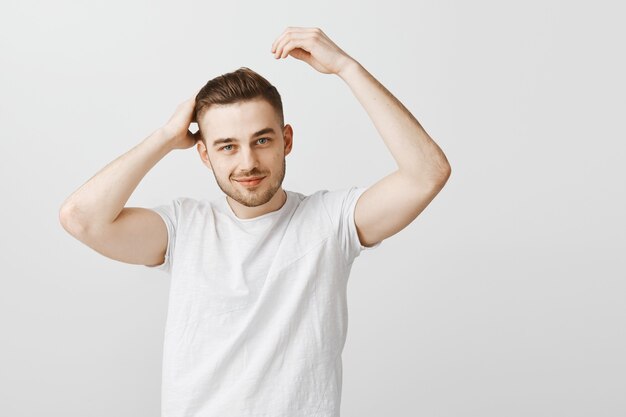 Sfacciato bell'uomo soddisfatto del nuovo taglio di capelli dopo il barbiere