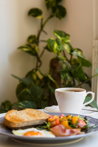 Sfocatura colazione e tè sul tavolo di fronte alle piante