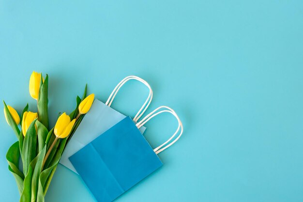 Sfondo blu piatto con fiori e sacchetti di carta