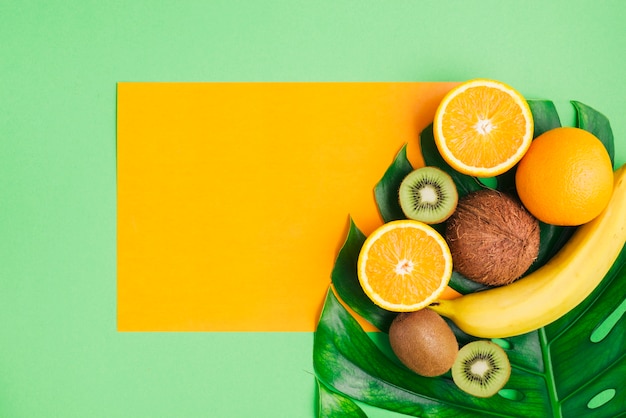 Sfondo di frutti tropicali con modello di scheda e foglia di palma