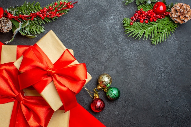 Sfondo di Natale con bellissimi doni con nastro a forma di fiocco e accessori per la decorazione di rami di abete su un tavolo scuro