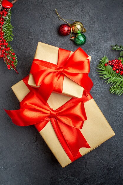 Sfondo di Natale con bellissimi regali con nastro a forma di arco e accessori per la decorazione di rami di abete su un tavolo scuro sopra la vista