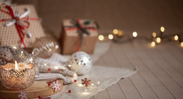 Sfondo di Natale con candela accesa decorativa in argento, luci e confezioni regalo su uno sfondo sfocato. Copia spazio.