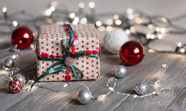 Sfondo di Natale con confezione regalo da vicino su superficie in legno, palle di Natale e luci bokeh, spazio copia.