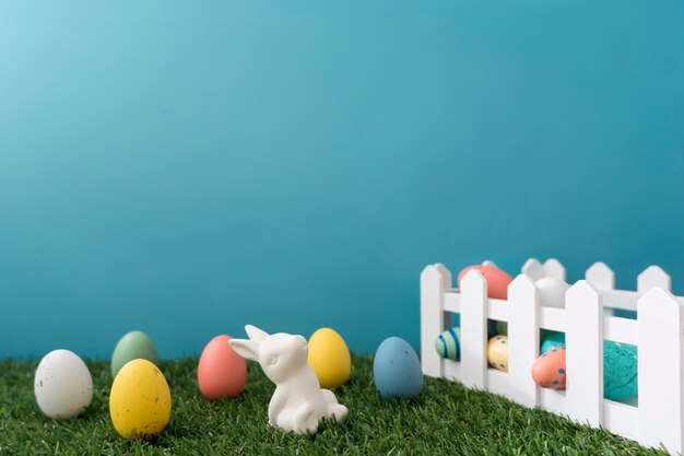 Sfondo di Pasqua con le uova colorate, recinzione in legno e coniglio