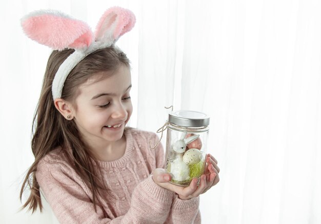 Sfondo di Pasqua con una ragazza con le orecchie da coniglio e lo spazio della copia dell'arredamento