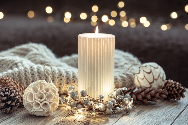 Sfondo festivo invernale con candela accesa e dettagli di decorazioni per la casa su sfondo sfocato con bokeh.