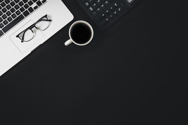 Sfondo nero piatto con tazza da caffè portatile e vista dall'alto della calcolatrice