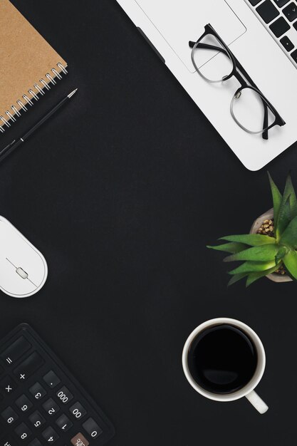 Sfondo nero piatto con tazza di caffè per laptop e vista dall'alto della calcolatrice