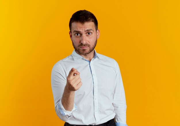 Sguardi e punti bell'uomo serio isolati sulla parete arancione