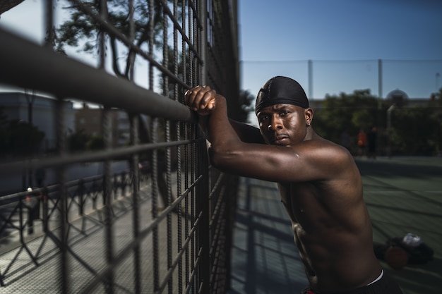 Shallow focus shot di un uomo seminudo afro-americano appoggiato alla recinzione