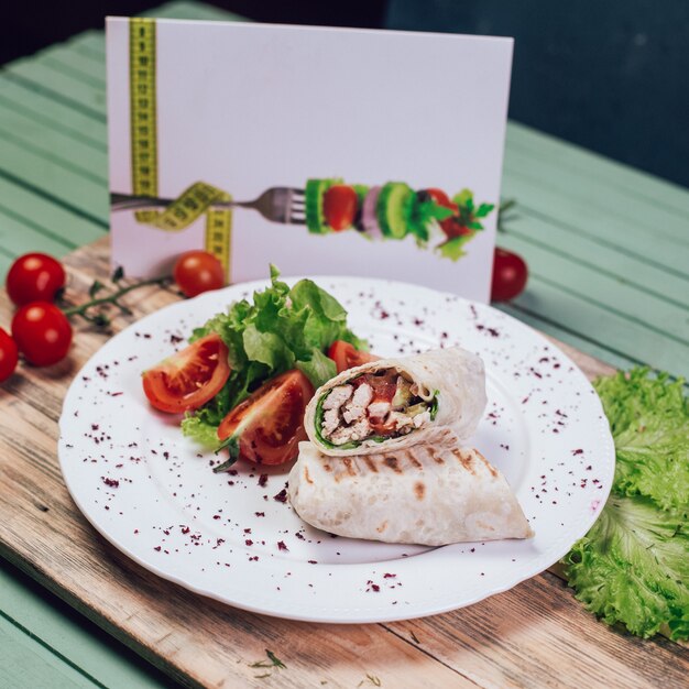 Shaurma arabo dell'alimento della via con insalata di verdure su un bordo di legno.