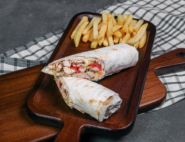 Shaurma arabo dell'alimento di via avvolto con pane di lavash e con le patate fritte.