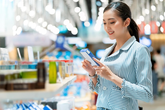 Shopping femminile asiatico attraente con felicità e allegro sul supermercato sfocatura centro commerciale bokeh backgroundoung Donna asiatica con carrello spesa per prodotti freschi