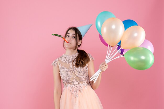 si chiedeva la ragazza festaiola con il tappo del partito che tiene palloncini usando il generatore di rumore sul rosa