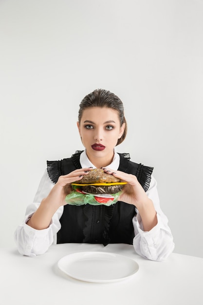 Siamo quello che mangiamo. Hamburger di mangiare della donna fatta di plastica, concetto di eco. Ci sono così tanti polimeri che ne siamo fatti. Disastro ambientale, moda, bellezza, cibo. Perdere il mondo organico.