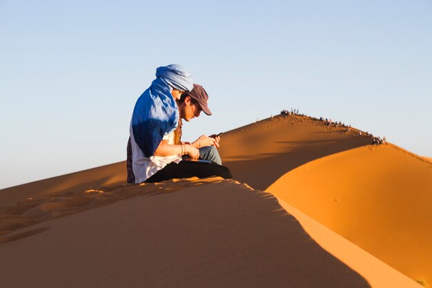 Sideview di due persone sedute sulla duna