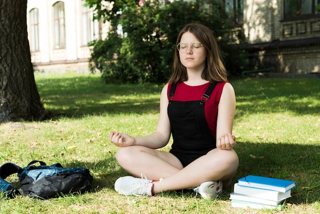 Sideview di meditare la ragazza del liceo