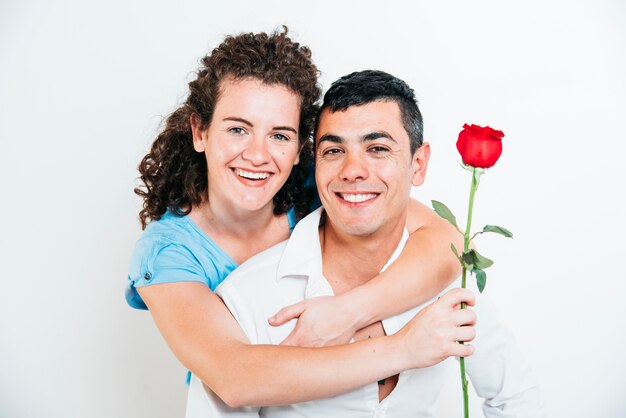 Signora allegra con il fiore che abbraccia il tipo sorridente