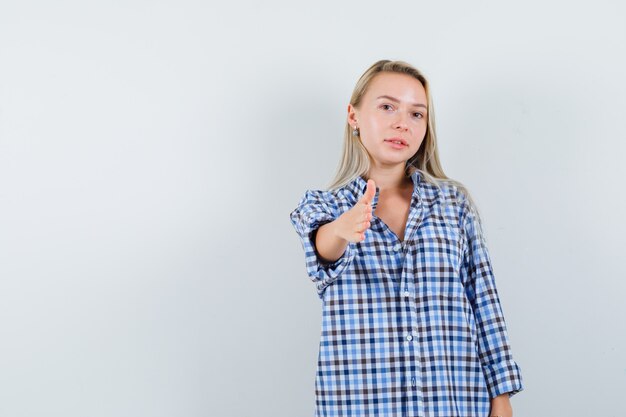 Signora bionda che dà la mano per tremare in camicia a quadri e sembrare gentile