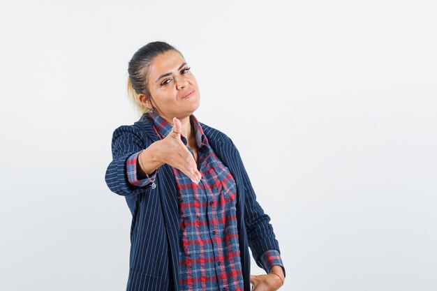 Signora bionda che dà la mano per tremare in camicia, giacca e sembra gentile, vista frontale.