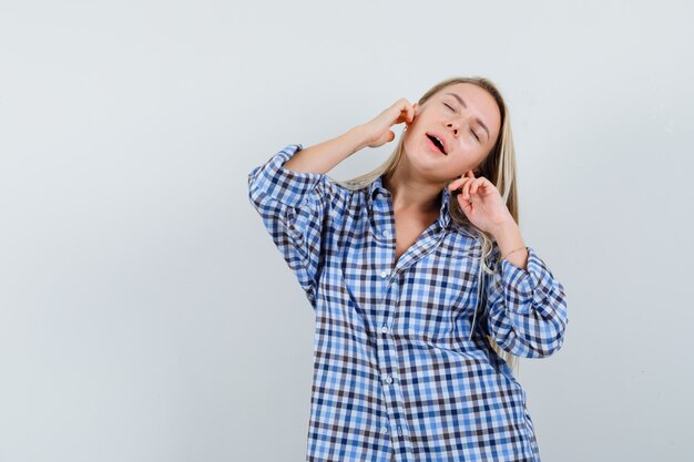 Signora bionda che finge di ascoltare musica in camicia casual e sembra felice