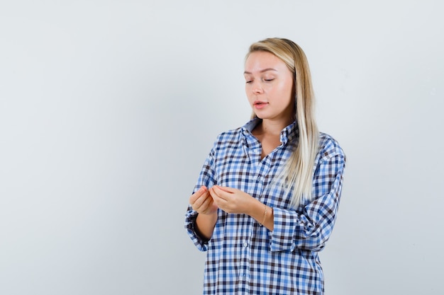 Signora bionda che finge di guardare qualcosa in camicia a quadri