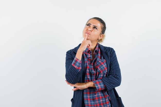 Signora bionda che tiene il dito sul mento in camicia, giacca e sembra sognante, vista frontale.