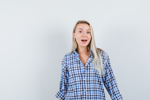 Signora bionda in camicia a quadri che guarda l'obbiettivo e guardando stupito